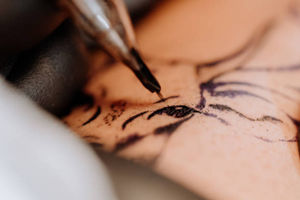 Close-up of tattoo needle depositing black tattoo ink into skin for fine lines.
