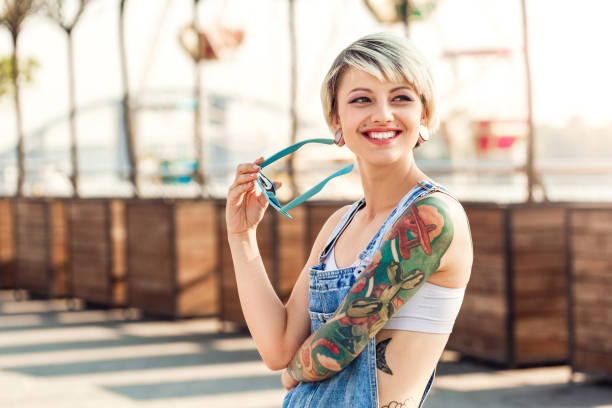 Smiling woman with vibrant arm tattoos outdoors
