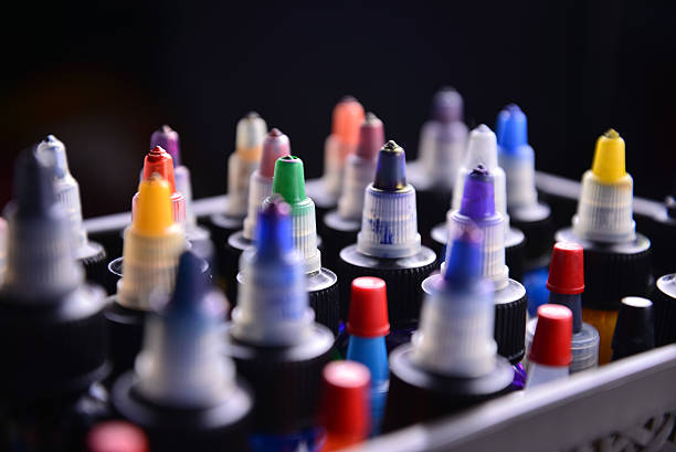 Assorted colorful bottles of tattoo ink arranged in tray.
