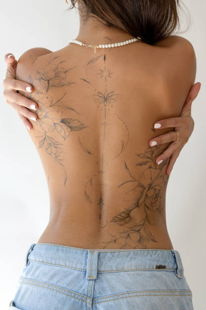 Woman’s back with floral line-art design—no tattoo ink visible yet.
