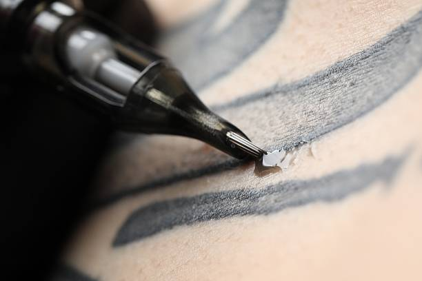 Tattoo needle deposits black tattoo ink into skin for bold linework.
