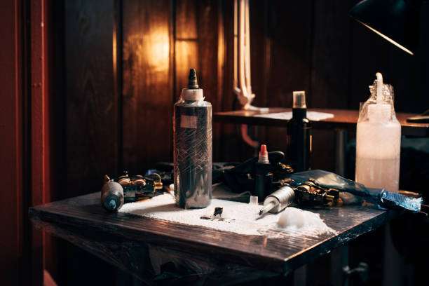 Tattoo artist's table with machines, bottles of tattoo ink, and supplies.