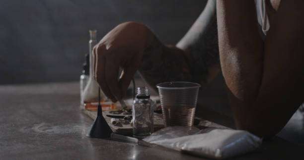 Artist's hand near bottles and supplies for mixing tattoo ink on a table.