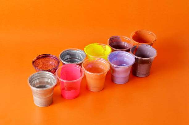 Colorful small cups with dried tattoo ink residue on a vibrant orange background.