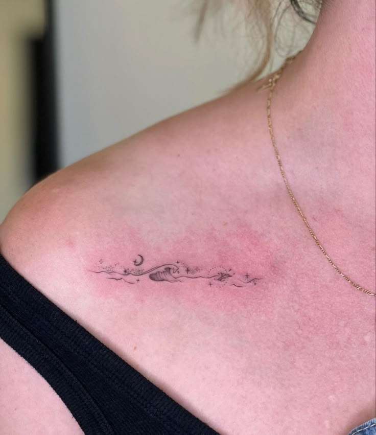 Delicate wave, moon, and stars tattoo on a collarbone, using fine line tattoo ink.
