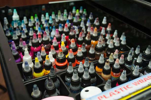 Tray filled with numerous vibrant bottles of professional tattoo ink for artists.