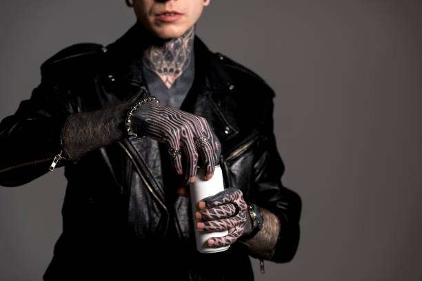 Heavily tattooed person opening a bottle, likely containing professional tattoo ink.