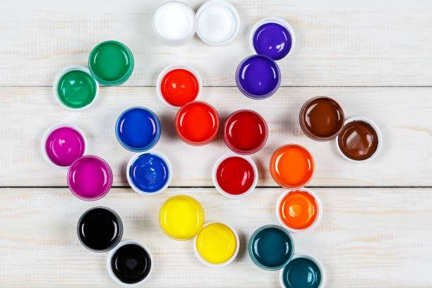 Overhead view of numerous vibrant, open pots of colorful tattoo ink.